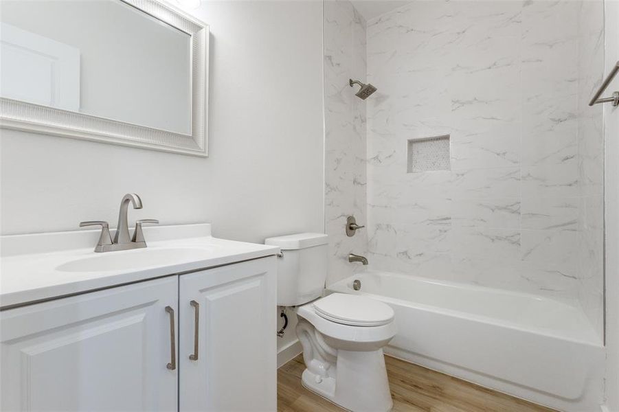 Full bathroom with toilet, hardwood / wood-style floors, vanity, and tiled shower / bath combo