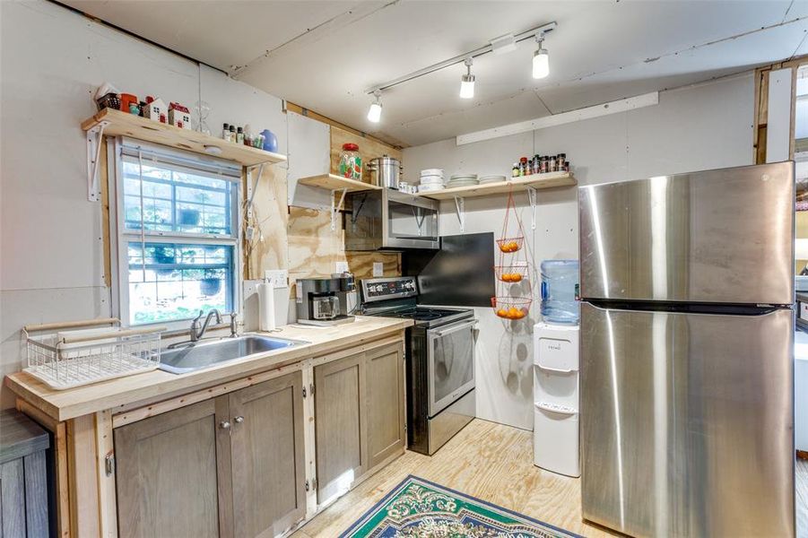 Kitchen with stainless steel appliances, light hardwood / wood-style floors, light brown cabinetry, and sink