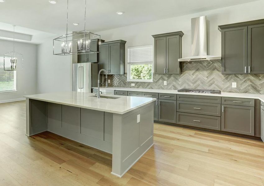 The kitchen has dark grey cabinetry, quartz countertops and stainless steel appliances.