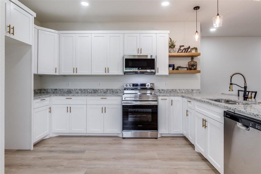 Kitchen featuring sink, light hardwood / wood-style flooring, white cabinetry, and appliances with stainless steel finishes