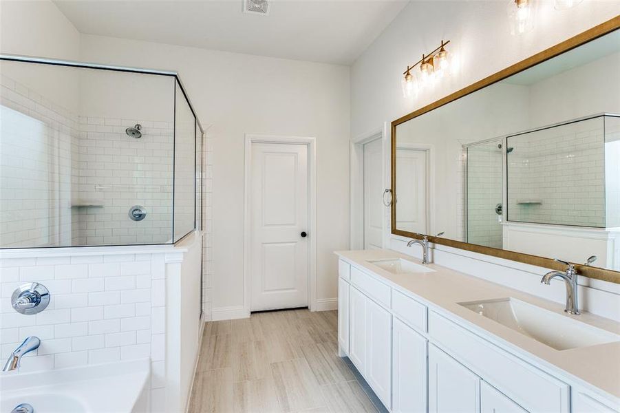 Bathroom featuring tile floors, dual bowl vanity, and a shower with shower door
