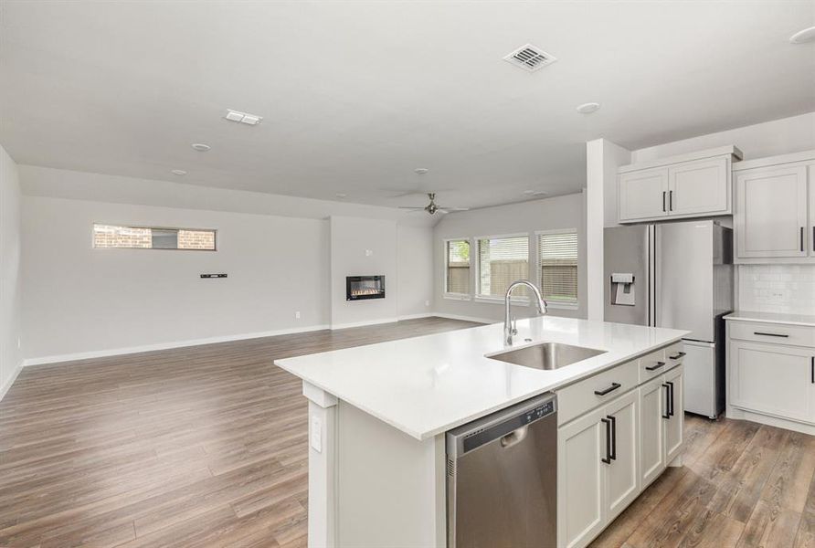 Kitchen featuring a center island with sink, stainless steel appliances, light wood-type flooring, and sink