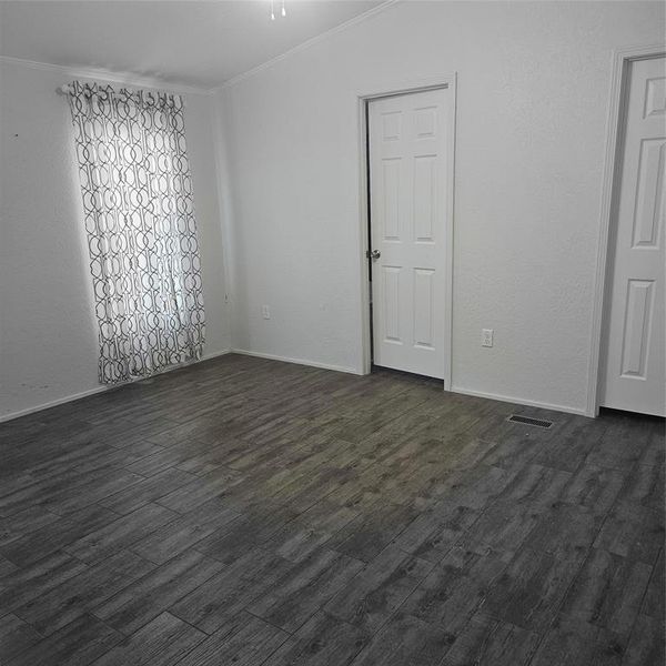 Empty room with dark hardwood / wood-style flooring and crown molding