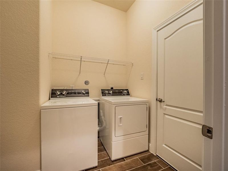 large laundry room located between the office and kitchen family area, tile floors and entrance to the 2 car garage