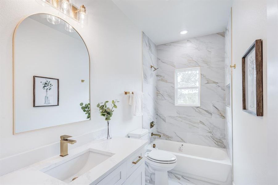 Full bathroom featuring tiled shower / bath, vanity, toilet, and tile flooring