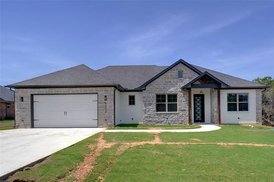 View of front facade featuring a garage and a front yard