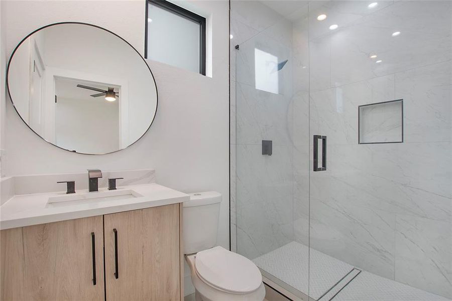 Bathroom featuring vanity, toilet, walk in shower, and ceiling fan