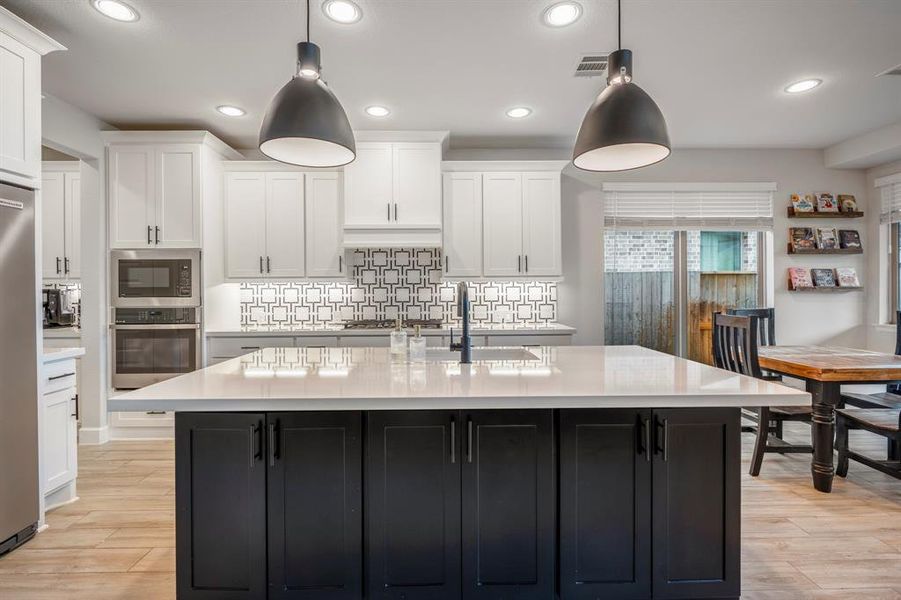 The kitchen boasts a deco wood paneled island with storage on both sides! Upgraded with built-in stainless steel appliances, a 5 burner gas cooktop, quartz countertops, and sleek white cabinets, this kitchen is ideal for cooking for the whole family or hosting holidays!
