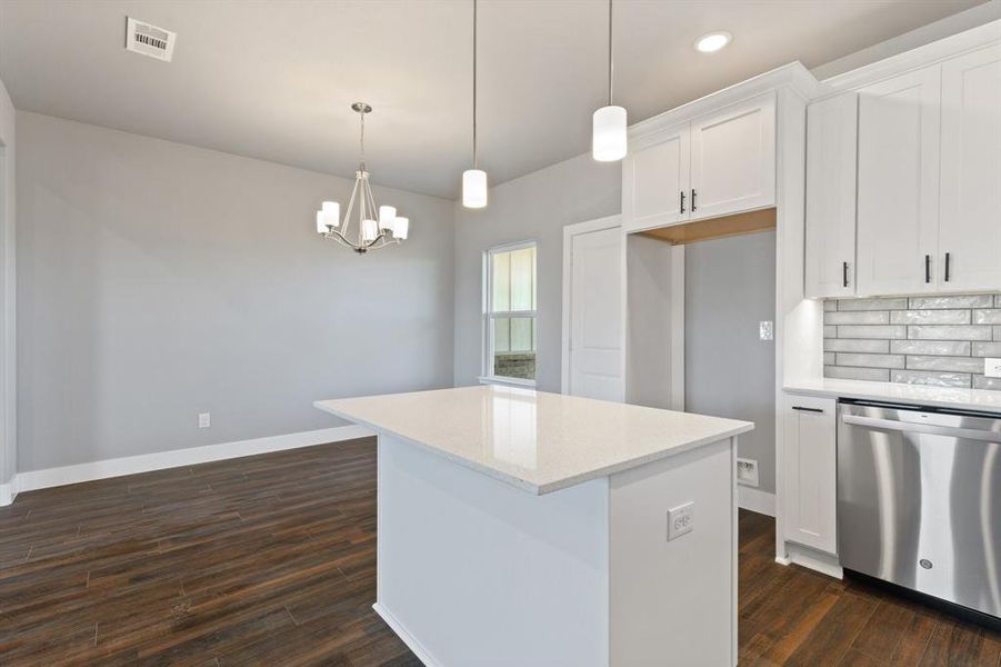 Kitchen with stainless steel dishwasher, dark hardwood / wood-style floors, white cabinetry, and hanging light fixtures