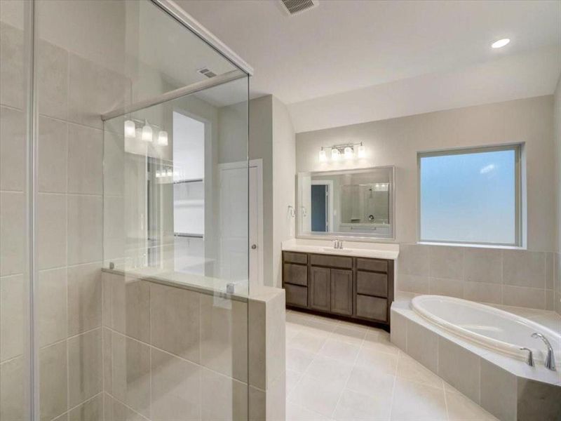 Elegant primary bathroom featuring a relaxing tub and a modern standing shower.