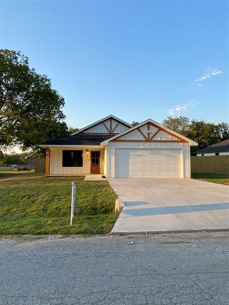 View of front of property with a garage and a front lawn