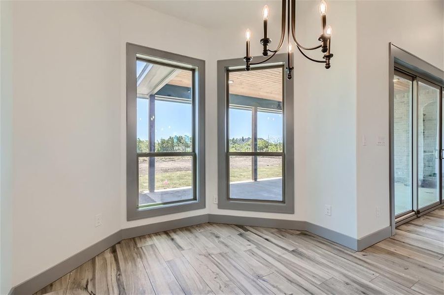 Unfurnished dining area featuring light wood-type flooring and a notable chandelier