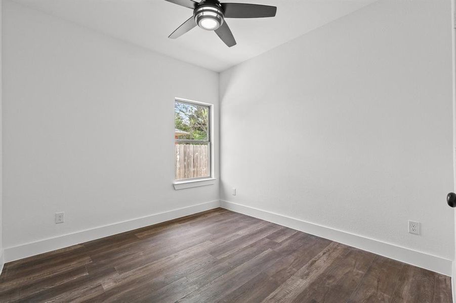 Unfurnished room featuring dark wood-type flooring and ceiling fan