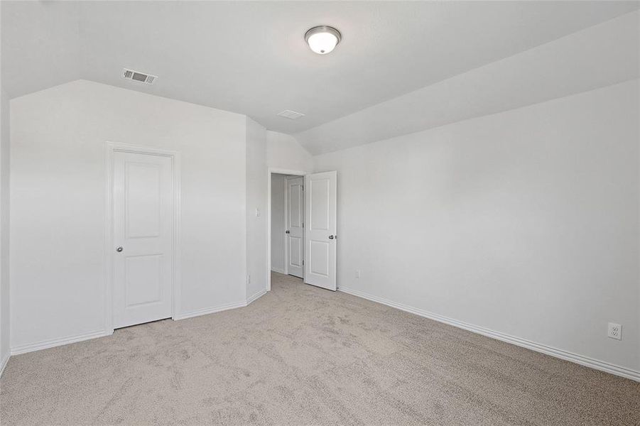 Unfurnished bedroom with light carpet and vaulted ceiling