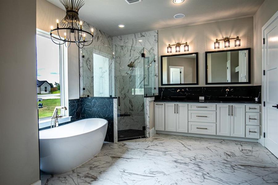 Primary bathroom featuring gorgeous tile patterned flooring, a notable chandelier, double vanity, tile walls, and separate shower and bath