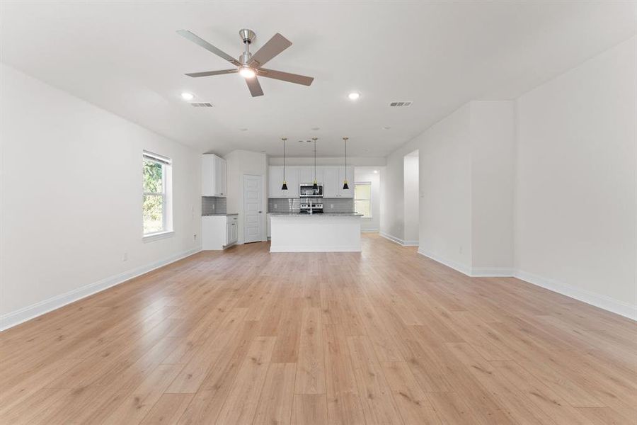 Unfurnished living room with light wood-type flooring and ceiling fan