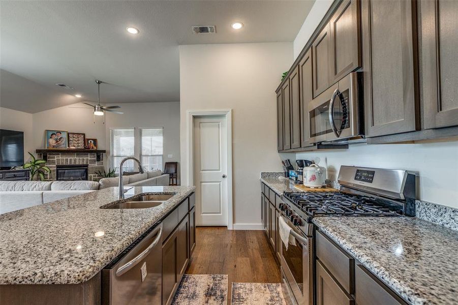 Kitchen with ceiling fan, sink, hardwood / wood-style flooring, stainless steel appliances, and a fireplace