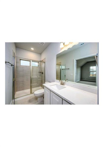 Bathroom featuring vanity, a shower with door, toilet, and plenty of natural light