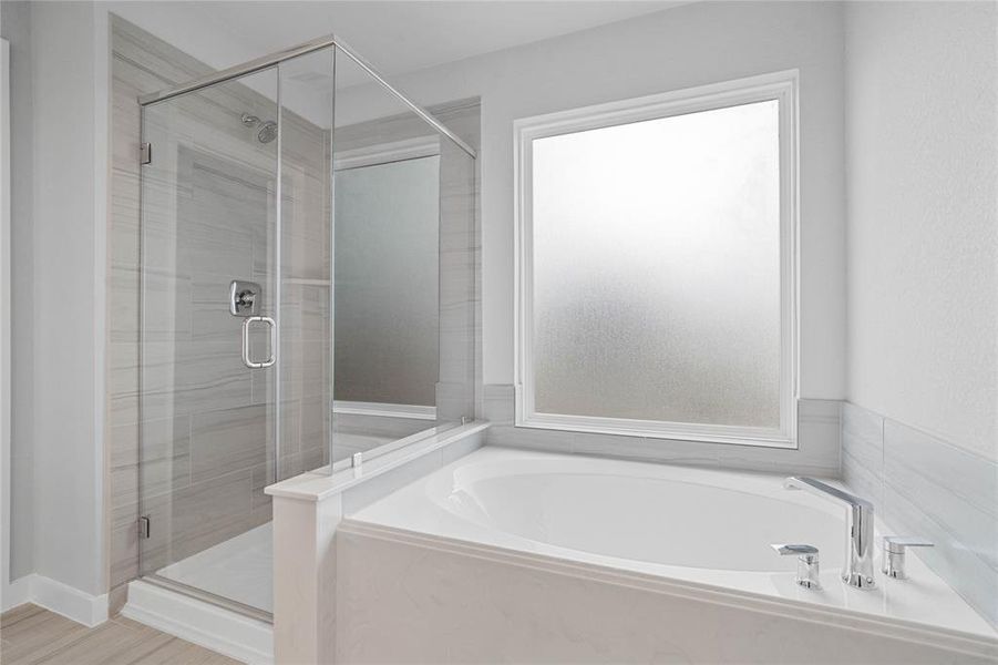 This additional view of the primary bath features a walk-in shower with tile surround and a separate garden tub perfect for soaking after a long day.