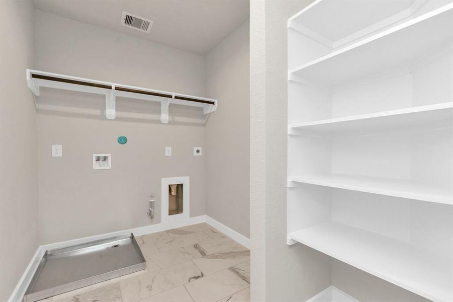 Located on second floor, a stylish laundry room where practicality meets a contemporary aesthetic. The dark finishes along with built in shelving, lend a sophisticated touch, creating a space that is both functional and visually appealing. Both electric and gas connections available. Sample photo of completed home with similar floor plan. As-built interior colors and selections may vary.