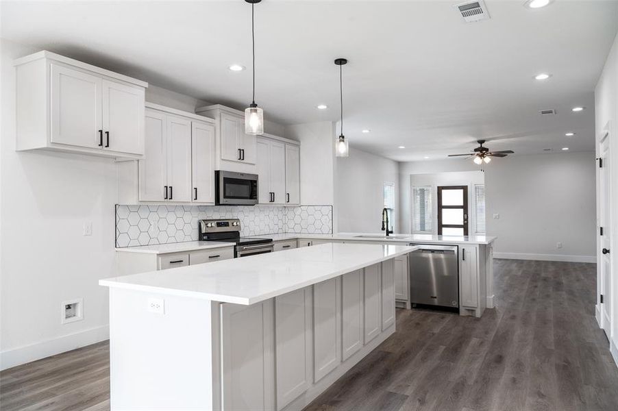 Kitchen featuring dark hardwood / wood-style floors, stainless steel appliances, backsplash, and hanging light fixtures