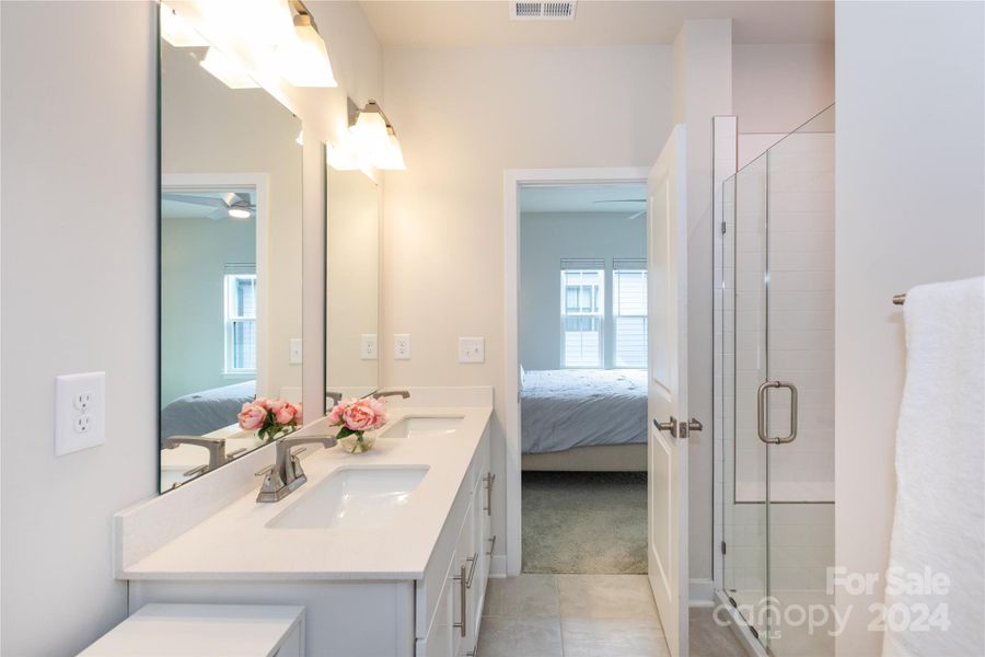 Primary bathroom with dual sinks, large shower, and access to walk-in closet.