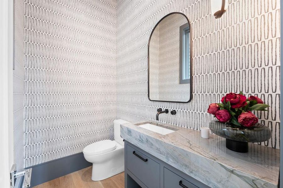 Discover the stylish bathroom just off the foyer featuring a stunning furniture piece cabinet, wall mounted faucet and hanging pendant lighting.