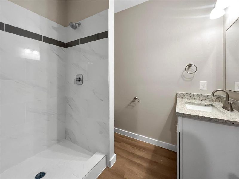 Bathroom featuring tiled shower, wood-type flooring, and vanity
