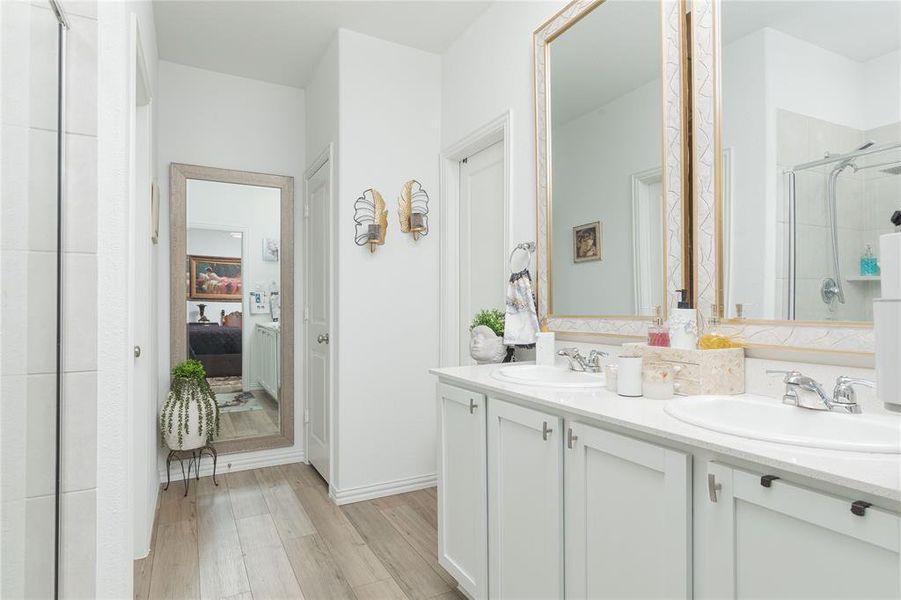 Bathroom featuring wood-type flooring, vanity, and a shower with door