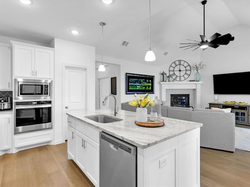 Kitchen with light hardwood / wood-style floors, appliances with stainless steel finishes, ceiling fan, and sink