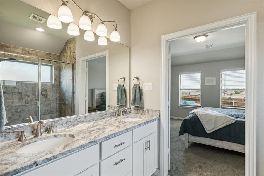 Bathroom with vanity with extensive cabinet space, an enclosed shower, and double sink