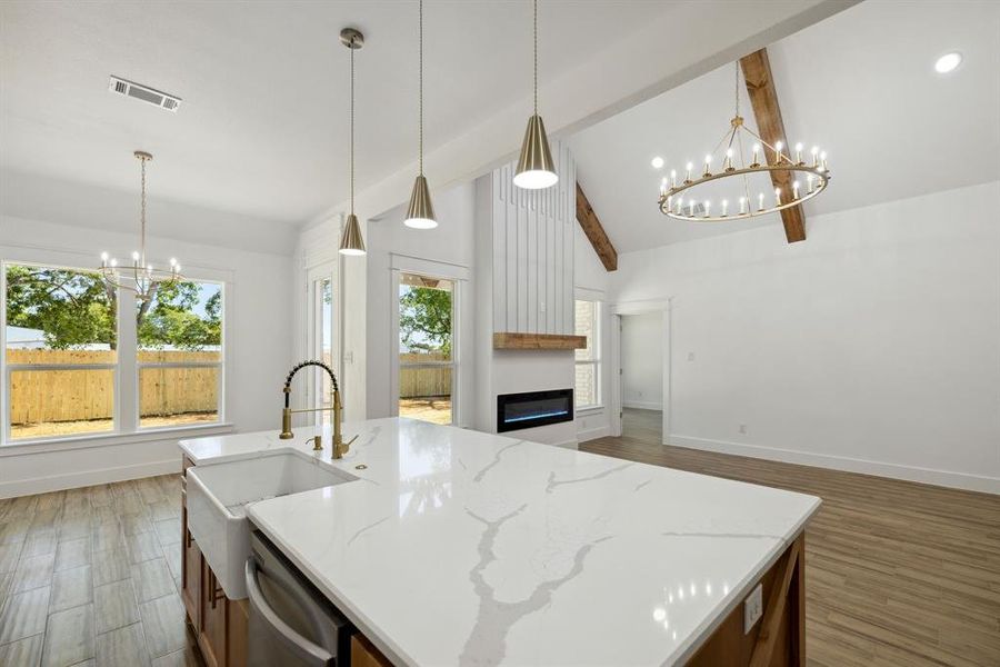 Kitchen featuring pendant lighting, light stone countertops, vaulted ceiling with beams, and dark hardwood / wood-style floors