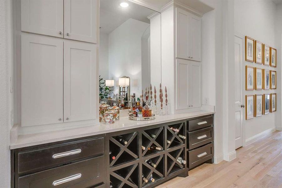 Bar with light hardwood / wood-style floors and white cabinetry