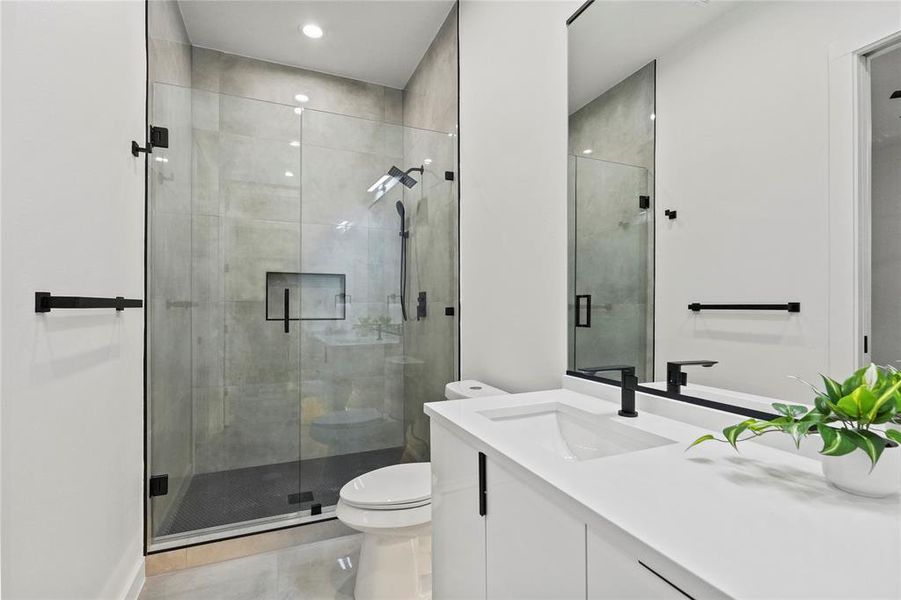 Bathroom with a shower with door, vanity, and toilet