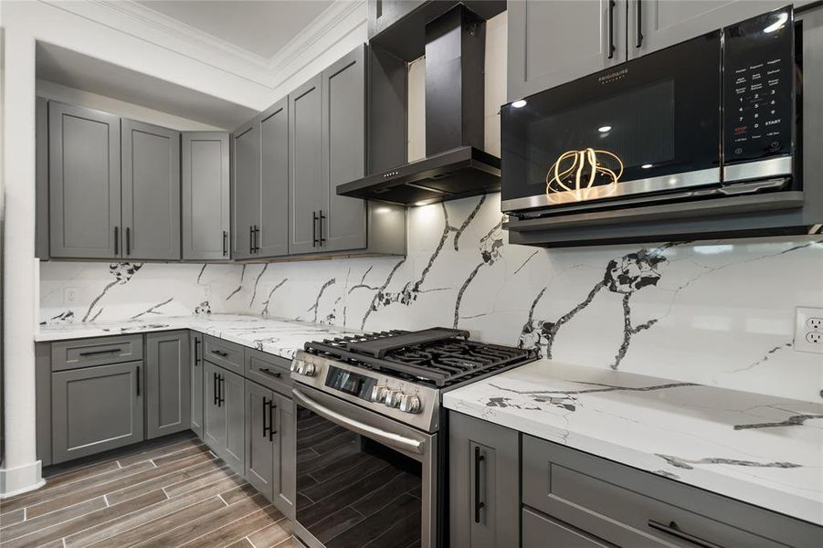 The black stainless steel range hood beautifully complements the quartz back splash