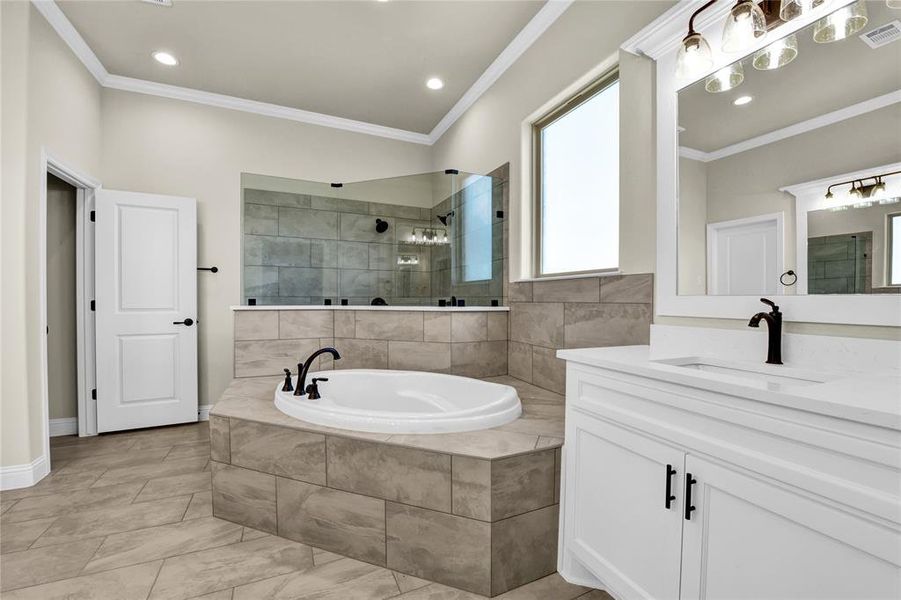 Bathroom with vanity, crown molding, and plus walk in shower