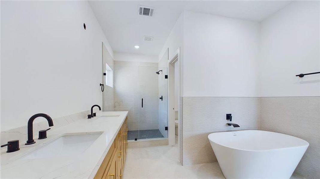 Primary bathroom boasts his and hers vanities, a private water closet, a glass-enclosed walk in shower, with an incredible soaking tub.