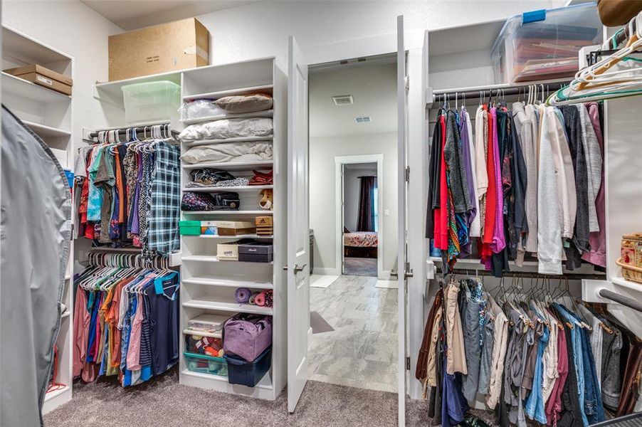 Spacious walk-in closet located between primary bath and utility room