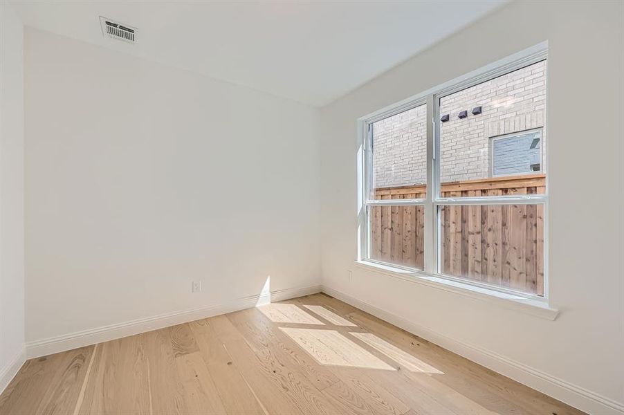 Empty room with light wood-type flooring and a healthy amount of sunlight