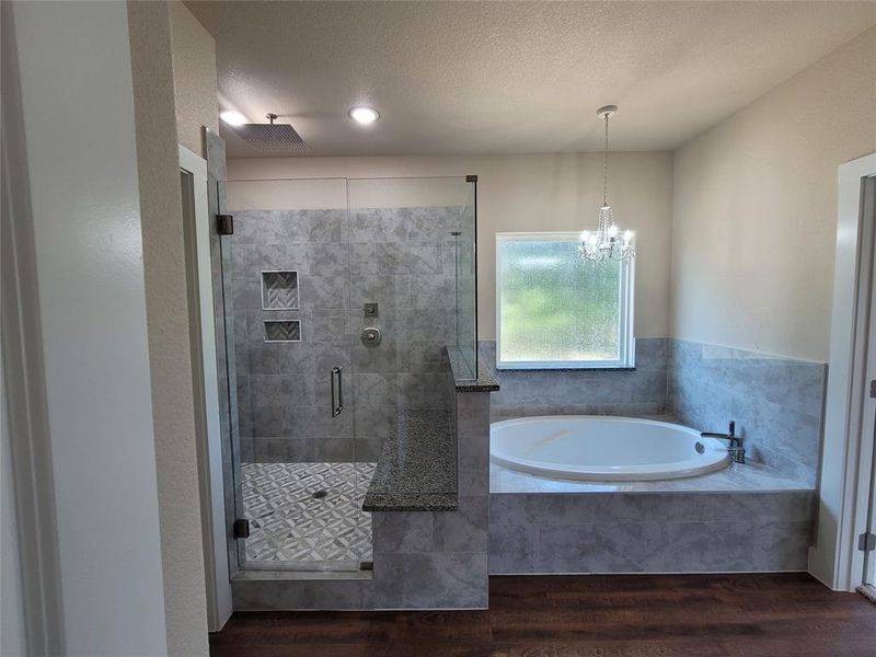 Bathroom with hardwood / wood-style floors, shower with separate bathtub, a notable chandelier, and a textured ceiling