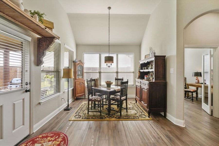 Dining area with high vaulted ceiling and hardwood / wood-style floors