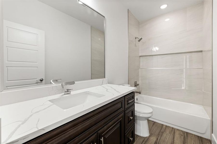 Full bathroom featuring wood-type flooring, vanity, toilet, and tiled shower / bath