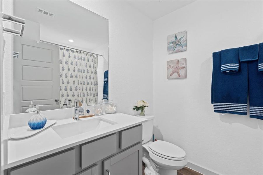 This is a modern and clean bathroom featuring a large vanity with ample storage, a full-sized mirror, a shower/tub combination.