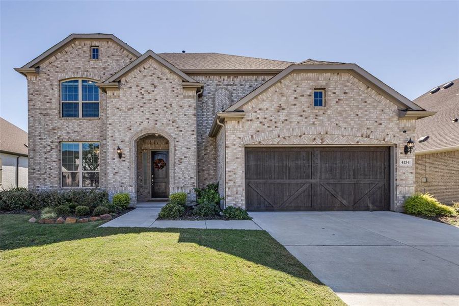 View of front of property featuring a garage and a front lawn