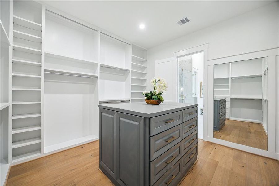 There is plenty of room in this walk in closet with an island, built in mirror and shelves for shoes and purses.