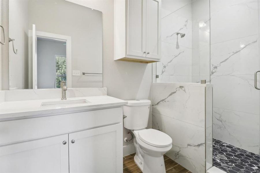 Bathroom with wood-type flooring, vanity, a shower with shower door, and toilet