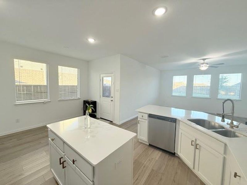 Kitchen featuring light hardwood / wood-style floors, a center island with sink, white cabinets, sink, and stainless steel dishwasher