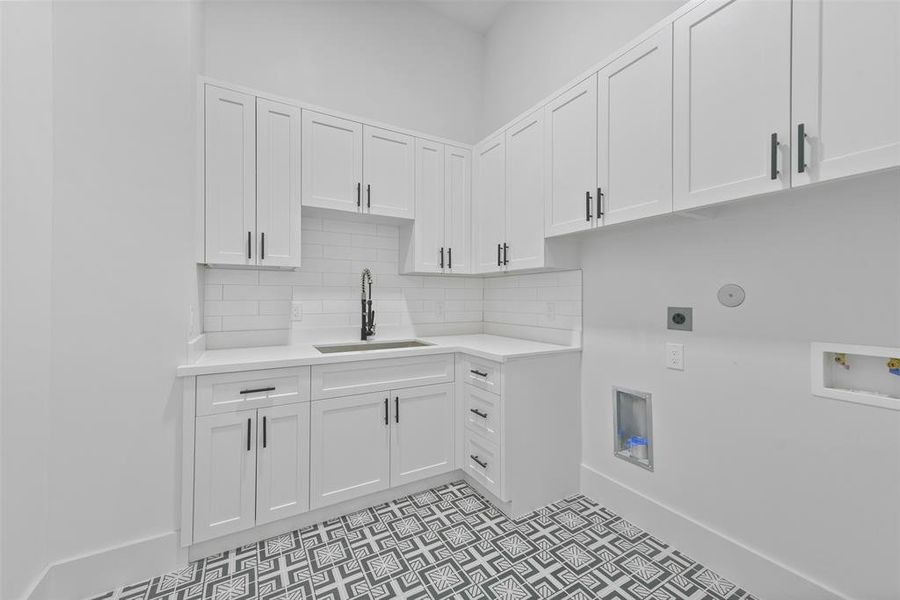 Impressive full sized laundry room located on the main level of the home includes a stainless steal sink and cabinetry for additional storage.