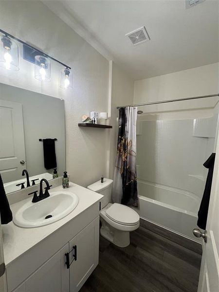 Full bathroom with toilet, hardwood / wood-style floors, vanity, and shower / tub combo