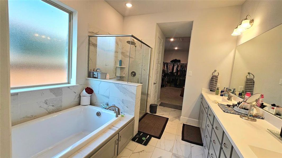 Bathroom featuring tile patterned flooring, double vanity, and plus walk in shower